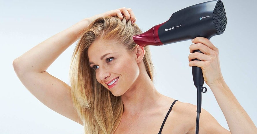 blonde woman using a blow dryer