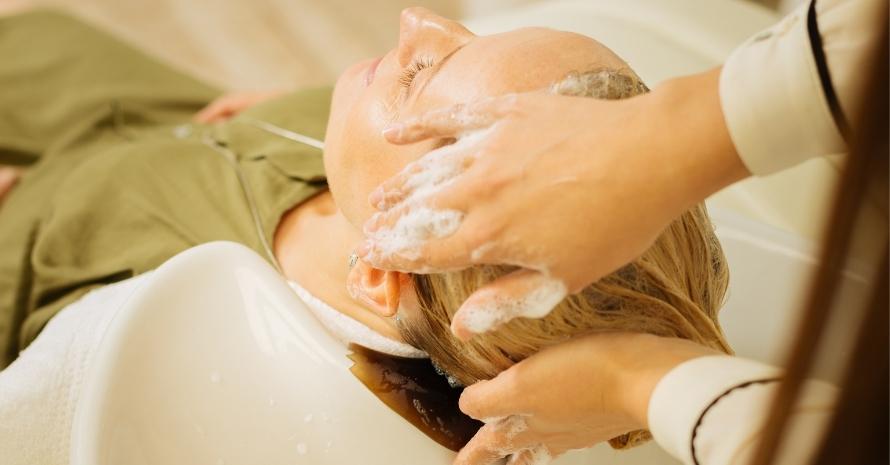 Skillful hairdresser applying shampoo