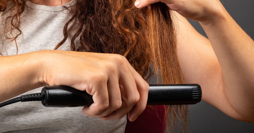 Girl Smooths Curly Hair with a Hair Straightener