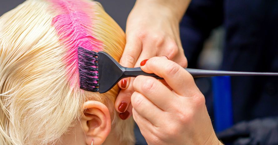 Hairdresser dyeing hair in pink