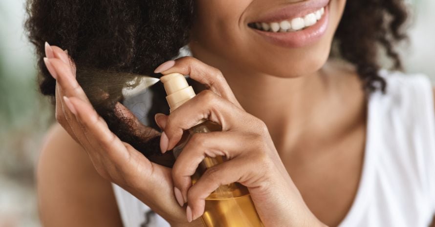 Woman Spraying Essential Oil On Curly Hair