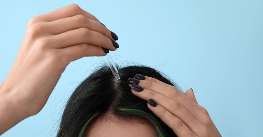 Woman applying oil to hair roots
