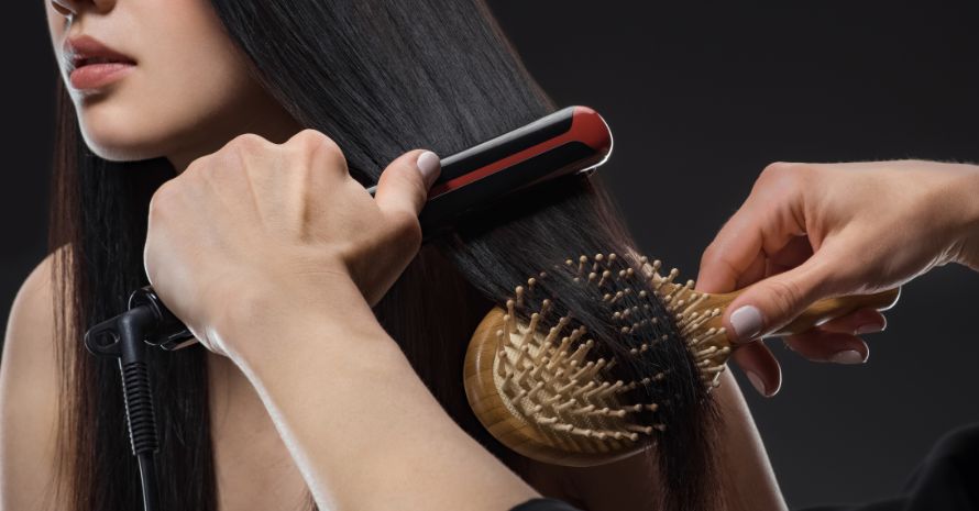 partial view of hair stylist straightening womans hair